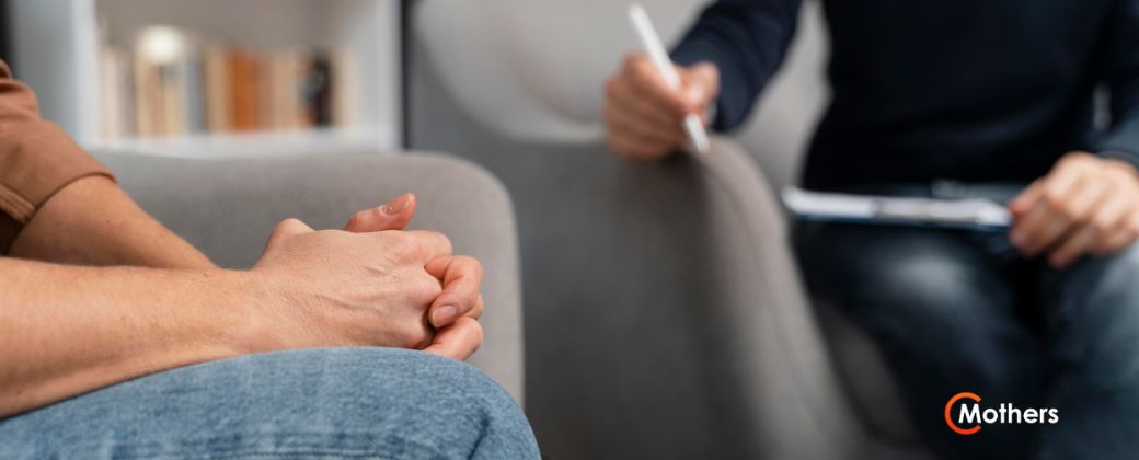 איך טיפול בCBT עוזר: פסיכולוג CBT יושב מול מטופל ורושם הערות ובצד ימין למטה לוגו של אתר "MOTHERS".